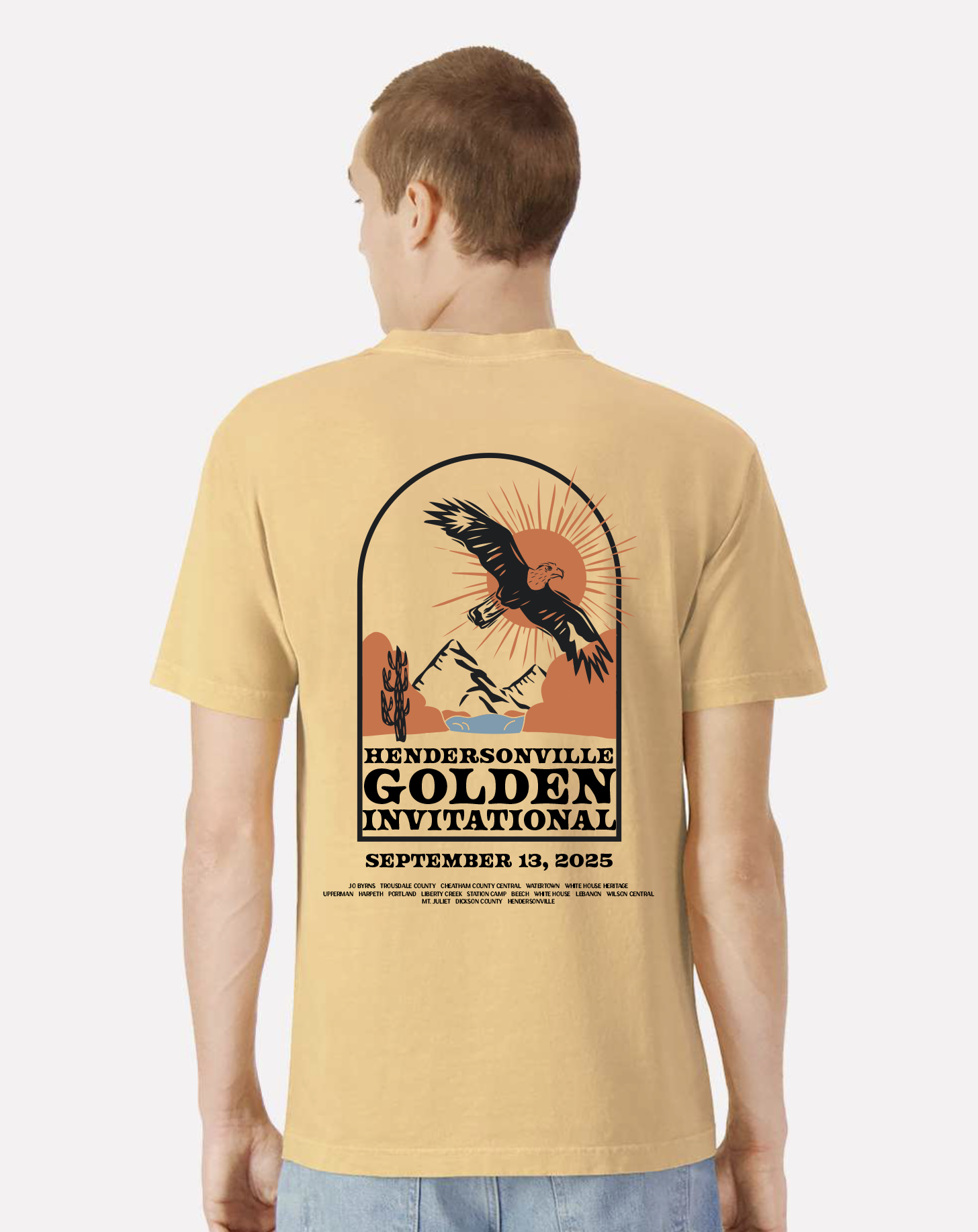 Person wearing a beige t-shirt with a graphic design and text on the back about a marching band contest
