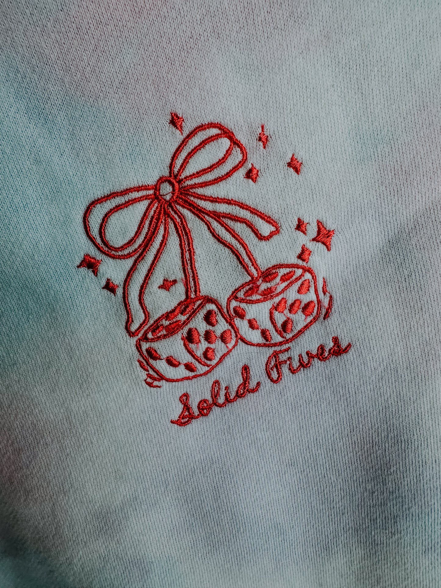 Embroidered design of shoes with a bow and 'Solid Fives' text on a light fabric background