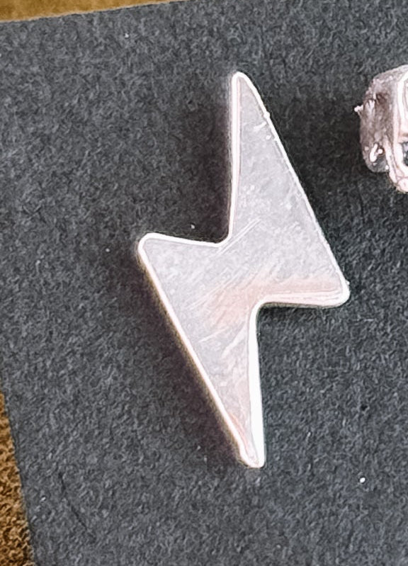 Silver lightning bolt-shaped earring on a dark background