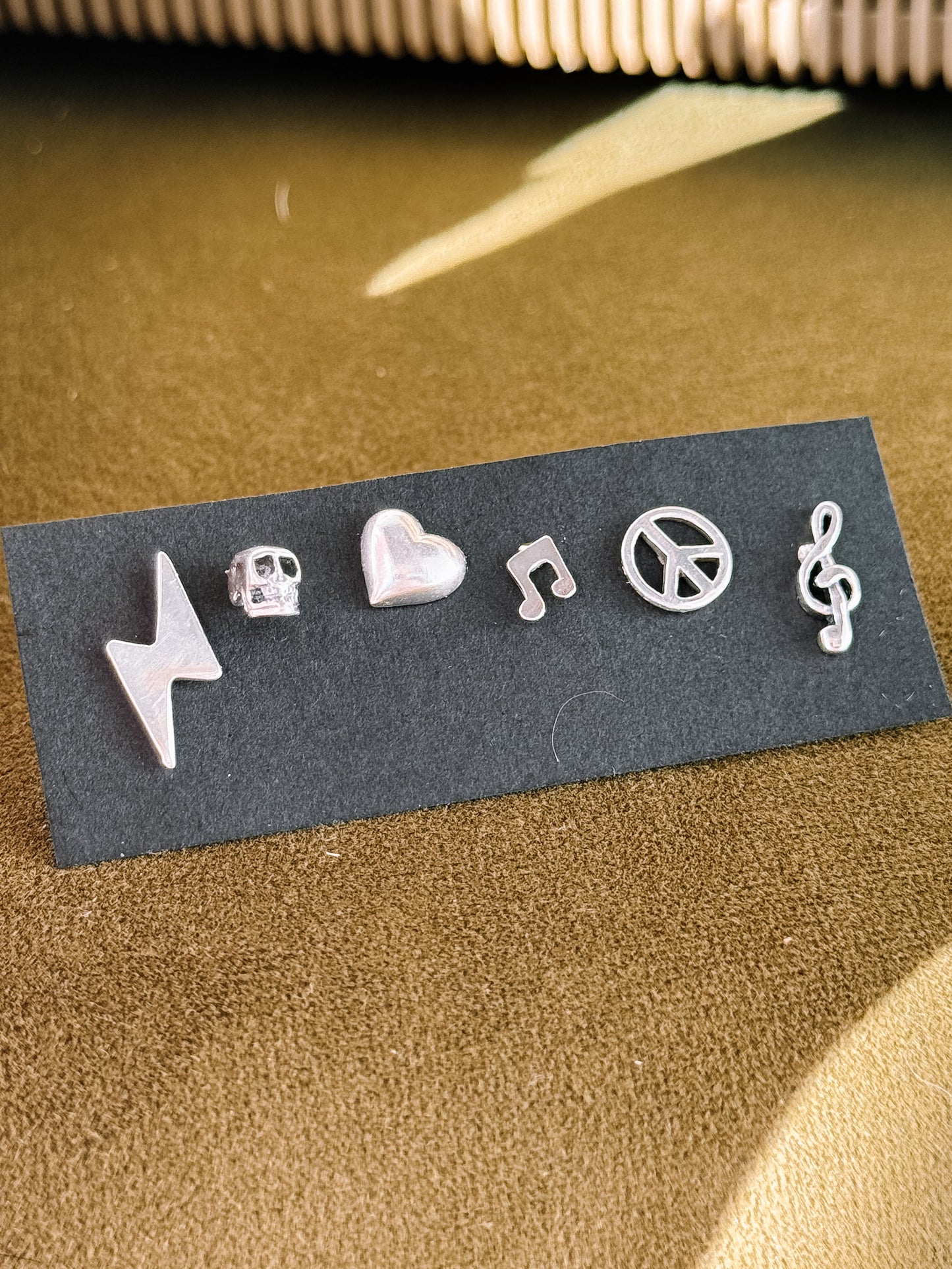 Set of silver musical earrings on a black card with a textured surface