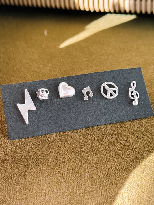 Set of silver musical earrings on a black card with a textured surface