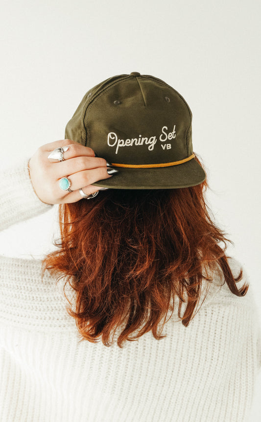Person wearing an olive green cap with 'Opening Sal' text on a white background