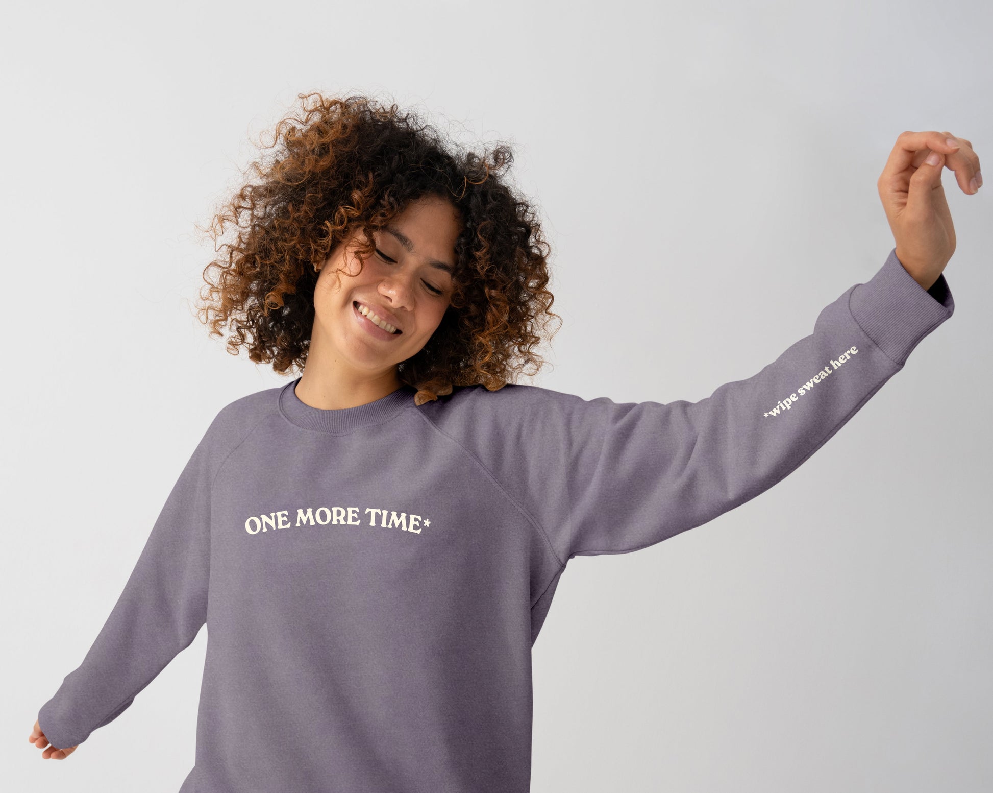 Person wearing a purple sweatshirt with 'ONE MORE TIME' text on a plain background